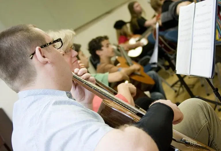 Adult learners playing classical guitar in group ensemble rehearsal