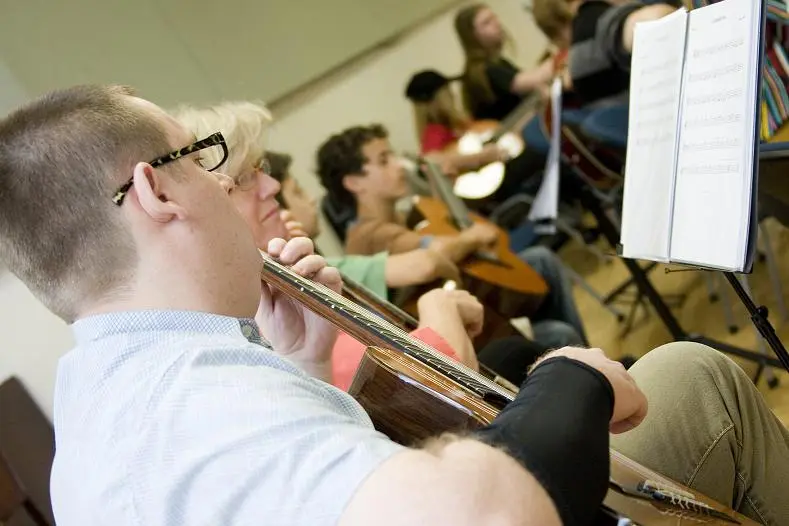 Adult learners playing classical guitar in group ensemble rehearsal